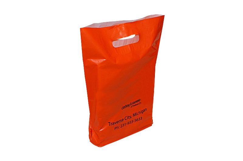 Boutique Bags – a red plastic shopping bag with a die-cut handle and black printed text including a phone number and location in Traverse City, Michigan.