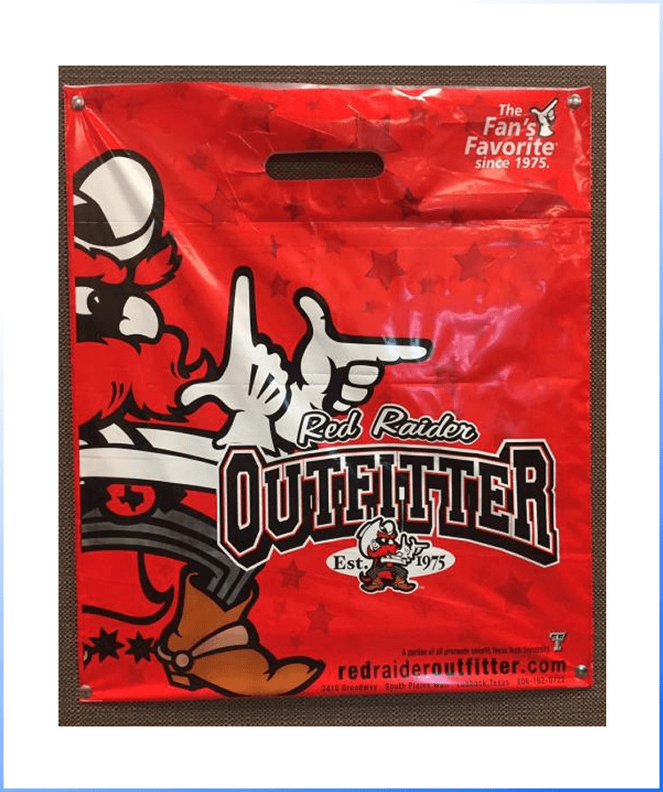 Red plastic shopping bag featuring a cartoon cowboy mascot, "Red Raider Outfitter" text, and branding details for a retail store established in 1975.