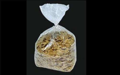 A transparent plastic bag filled with breakfast cereal is tied at the top, shown against a black background.