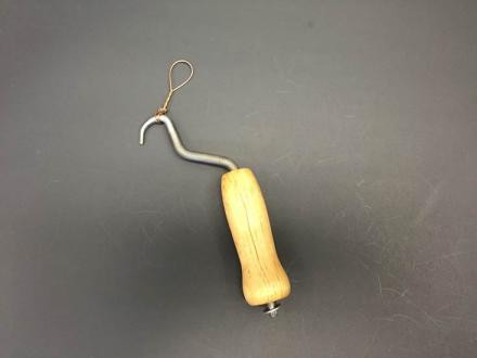 Sand/Soil Bags – a tool with a curved metal hook, wooden handle, and a wire loop at the end, displayed on a plain surface.