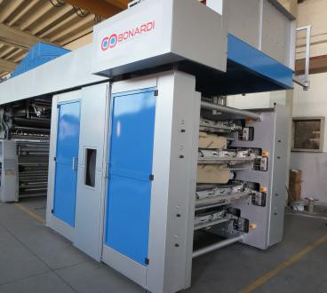 Large industrial printing machine with blue and gray panels, multiple rollers, and the Bonardi logo, situated in a warehouse setting.