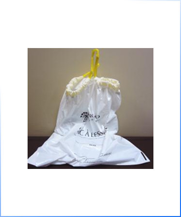 A white plastic laundry bag with yellow drawstrings is placed on a dark surface against a plain beige background.