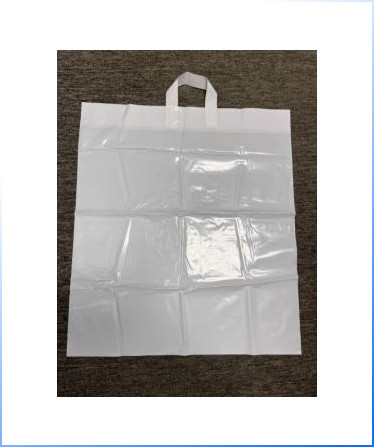 A large, flat, white plastic bag with two handles lying on a brown carpeted surface.