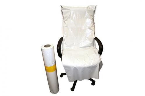 An office chair is covered with a large plastic sheet, with a roll of similar plastic sheeting standing next to it.