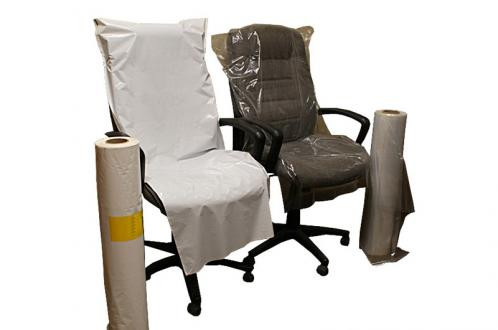 Two office chairs are covered with protective plastic sheets, with two large rolls of plastic sheeting placed next to them.