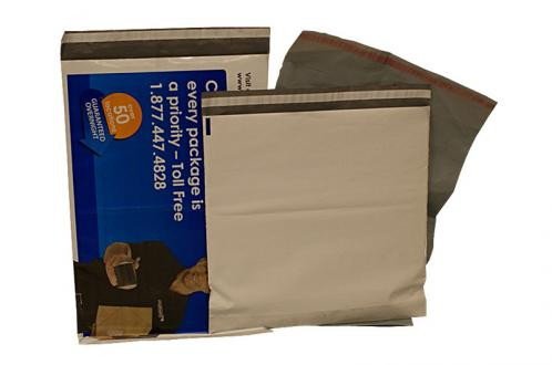 A gray poly mailer partially covers a blue and white shipping envelope, both used for mailing packages.